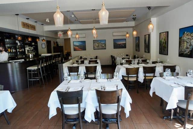 Inside Pasquale's Trattoria are tables with white tablecloths.